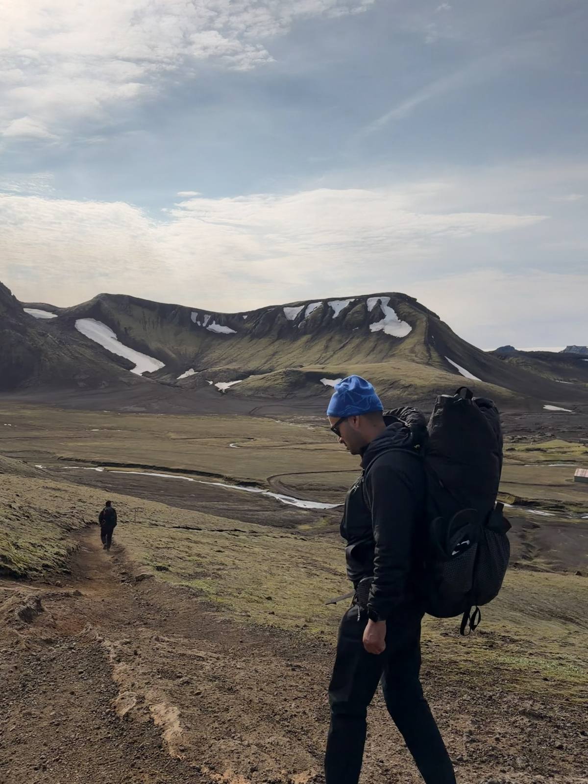 Hiker walking through the highlands with mountains and river behind
